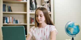 Dziewczynka odrabiająca lekcje na laptopie