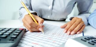 Przypomnienie o opłacie za użytkowanie wieczyste i opłacie za przekształcenie użytkowania wieczystego w prawo własności Zdjęcie osoby rozliczającej rachunki i piszącej ołówkiem w tabeli